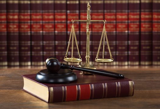 Closeup of mallet and legal book with justice scale on table in courtroom