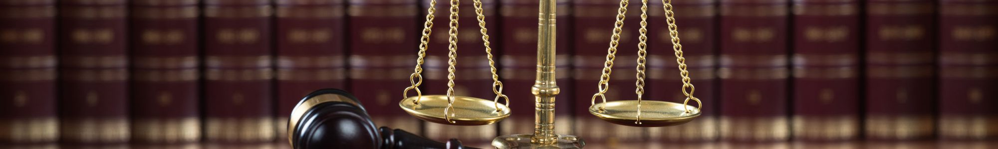 Closeup of mallet and legal book with justice scale on table in courtroom